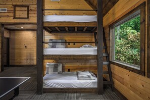 Habitación con literas de varios niveles y ventana con vistas a la vegetación.