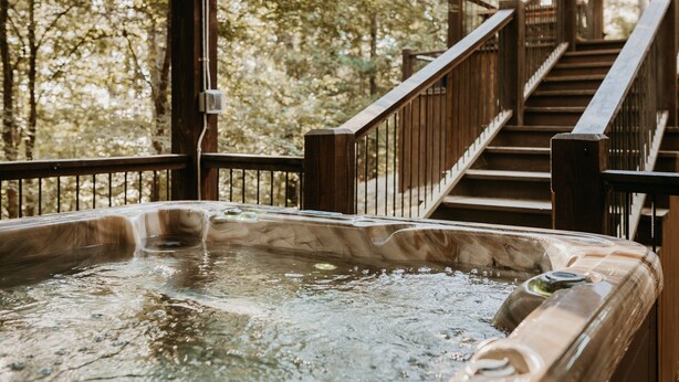 Ein Whirlpool mit einer Holzterrasse und einer Treppe zu einem überdachten Bereich.