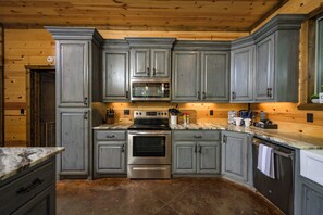 Una cocina con gabinetes grises, un horno de acero inoxidable y una zona de bar con cafetera.