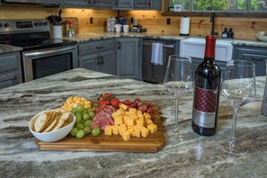 Una encimera de mármol con una tabla de embutidos, una botella de vino y dos copas.