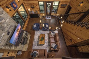A spacious living area with a stone fireplace, a round coffee table, and a leather sofa.