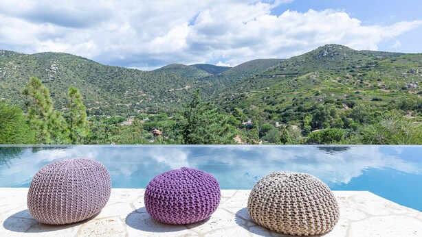 A poolside view with three knitted poufs and a mountainous landscape in the background. - Stunning villa with infinity pool, only 5 minute walk from the beach (Torre Delle Stelle (Maracalagonis))