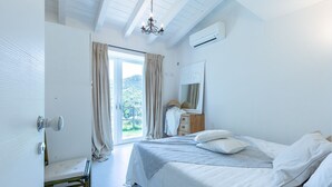A bedroom with a bed, a wooden dresser, a mirror, and a window with curtains. - Stunning villa with infinity pool, only 5 minute walk from the beach (Torre Delle Stelle (Maracalagonis))
