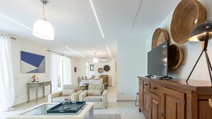 A modern living room with a glass coffee table, a sofa, a wooden cabinet, and a television. - Stunning villa with infinity pool, only 5 minute walk from the beach (Torre Delle Stelle (Maracalagonis))