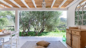A covered outdoor dining area with a table set for two, a bench, and a view of trees and hills. - Stunning villa with infinity pool, only 5 minute walk from the beach (Torre Delle Stelle (Maracalagonis))