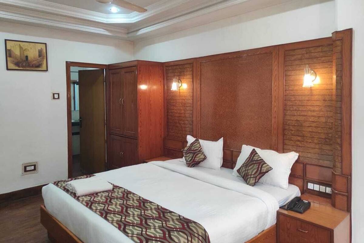 Quarto com uma cama grande, cabeceira de madeira, abajures e um ventilador de teto.