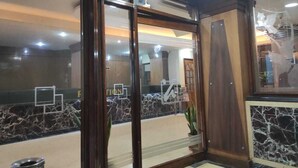 Un vestíbulo de hotel con un mostrador de recepción de mármol, puertas de madera y una planta en maceta.