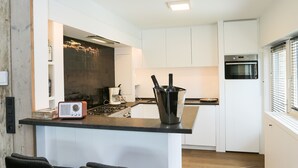 Een moderne keuken met een centraal eiland, barkrukken en een inbouwoven.