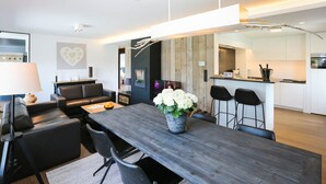 Een moderne woonkamer met een donker houten eettafel, zwarte leren banken en een potplant.