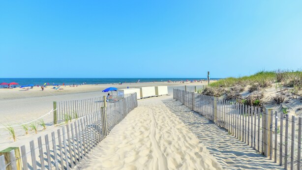 A sandy beach path with a wooden fence, leading to the beach. - Bluewater -3 Bedroom Condo with Outdoor Pool! (Ocean City)