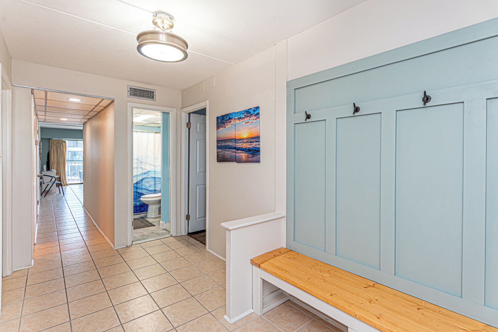 A hallway with a bench, a door, and a painting.