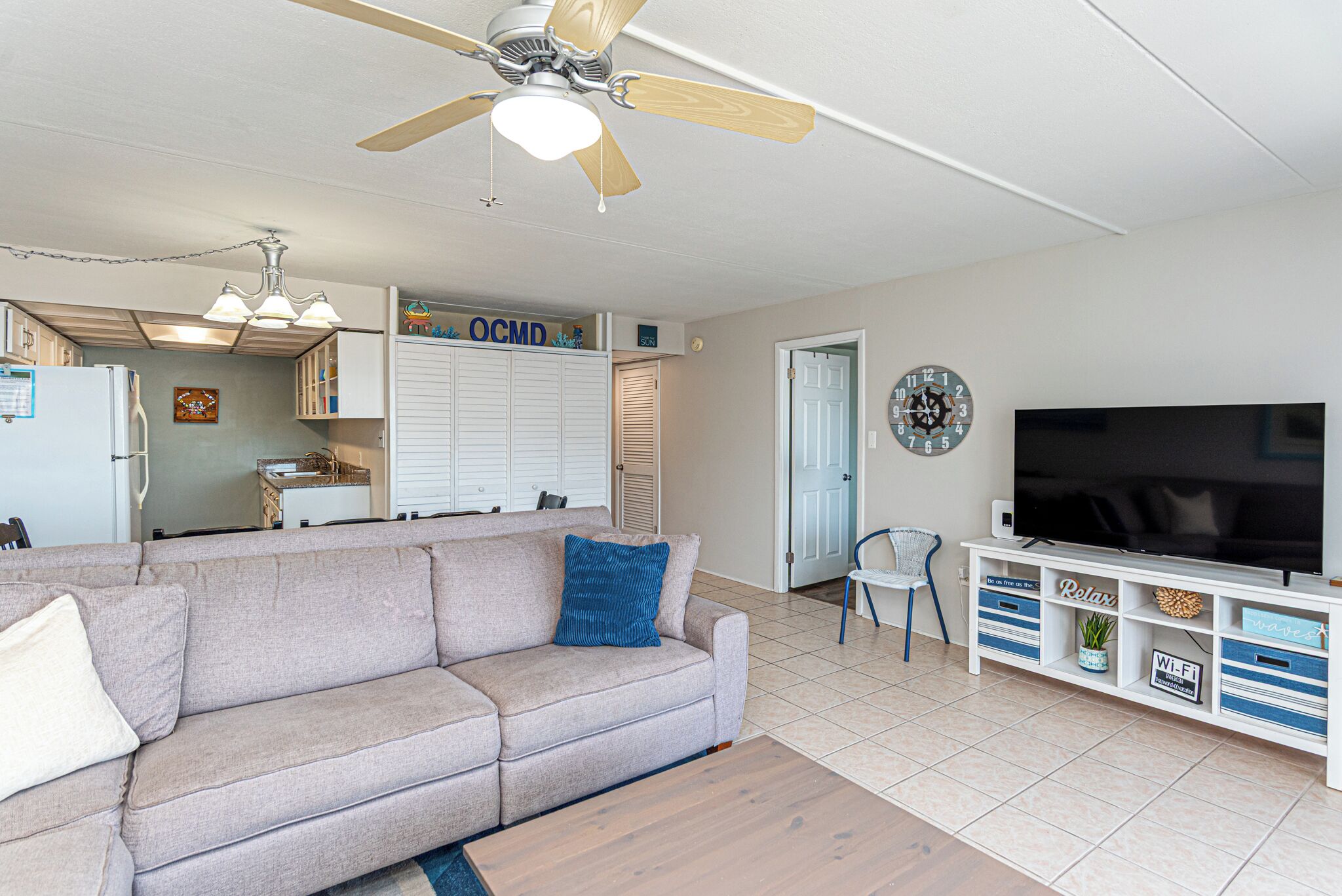 A living room with a sofa, a coffee table, a TV, and a ceiling fan.