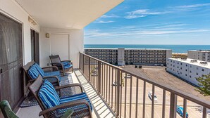A balcony with wicker furniture, a view of the ocean, and a parking lot. - Bluewater -3 Bedroom Condo with Outdoor Pool! (Ocean City)