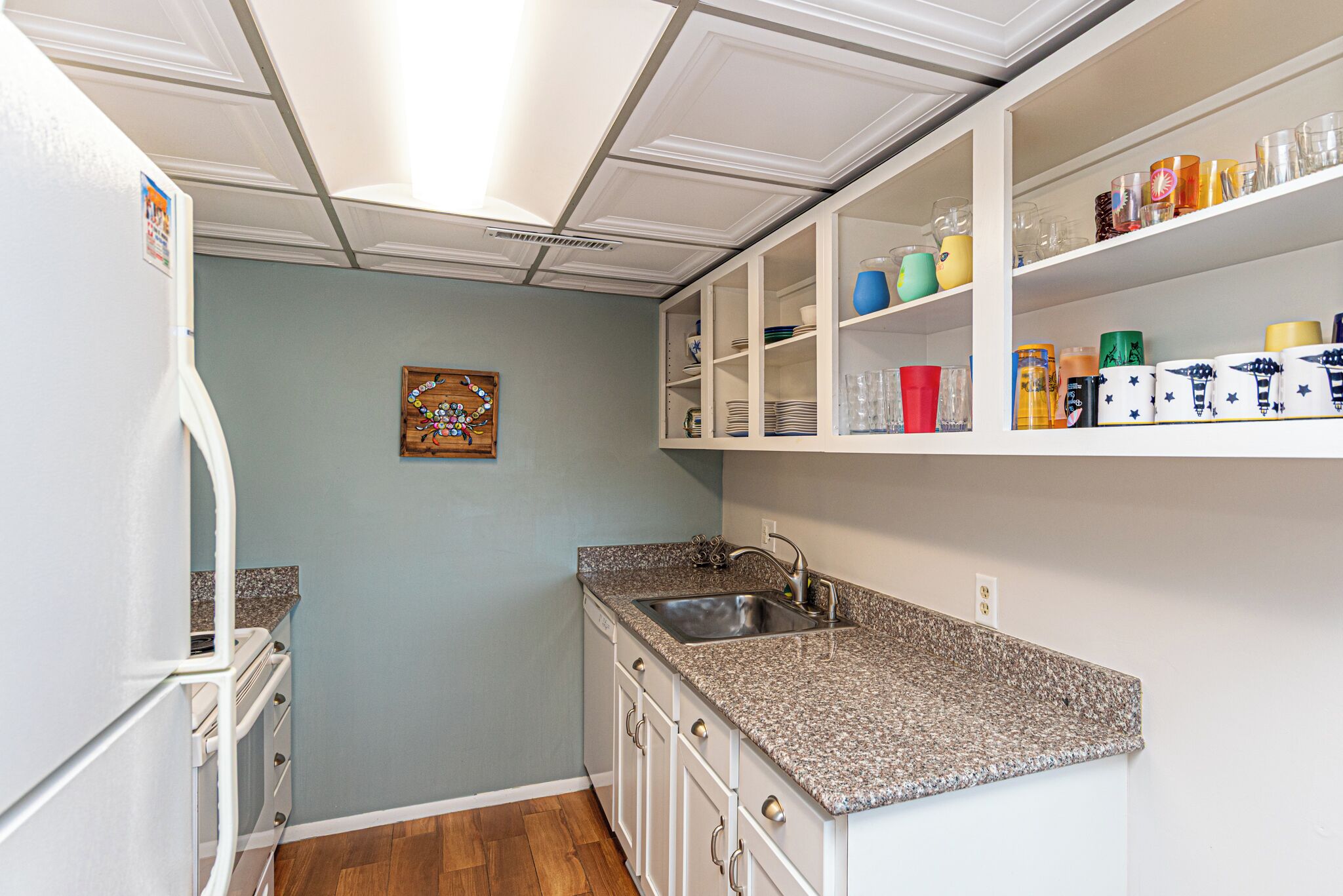 A compact kitchen with white cabinetry, a granite countertop, and a built-in sink.