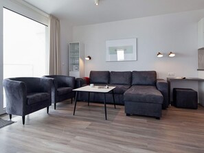 En moderne stue med sofasæt, et sofabord og et skrivebord med to lamper.