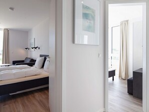 A modern hotel room with a bed, a seating area, and a view of the outdoors.