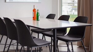 A modern dining area with a white table, black chairs, and two bottles on the table.