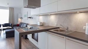 A modern kitchen with a built-in oven, a sink, and a dining area with a table and chairs.