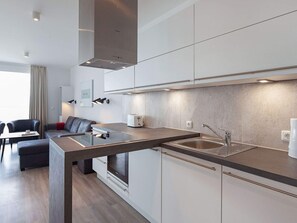 Une cuisine moderne équipée d’un four encastré, d’un évier et d’un coin repas avec une table et des chaises.