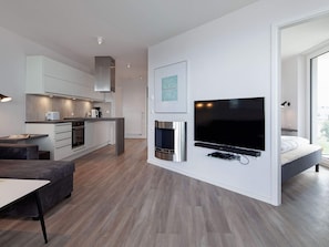 A modern living space with a kitchen, dining area, and a bedroom with a large window.