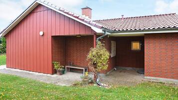 A red barn-style building with a tiled roof, a small porch, and a potted plant.