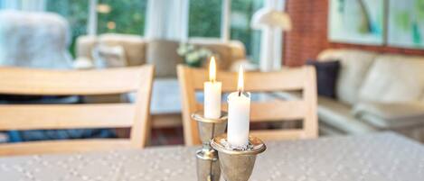 A dining area with a table set for two, featuring a candle centerpiece.
