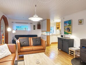 Un salon chaleureux avec un canapé en cuir, une table basse en bois et un coin cuisine équipé d’une cuisinière et de placards.