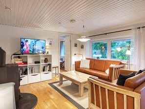 Una sala de estar con televisor, sofá, mesa de centro y estantería.