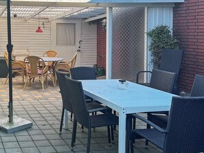 Une terrasse extérieure avec une table et des chaises, une porte et un mur en briques.
