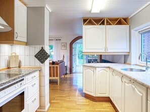 A kitchen with white cabinetry, a granite countertop, and a built-in oven. - 6 Person Holiday Home in Dannemare (Dannemare)