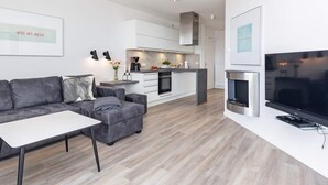 Un salon moderne avec un canapé gris, une table basse blanche et un téléviseur  à écran plat.