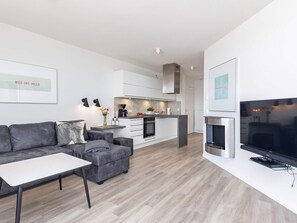 A modern living room with a grey sofa, a white coffee table, and a flat-screen TV.