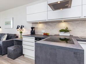 A modern kitchen with a central island, white cabinetry, and a coffee maker.