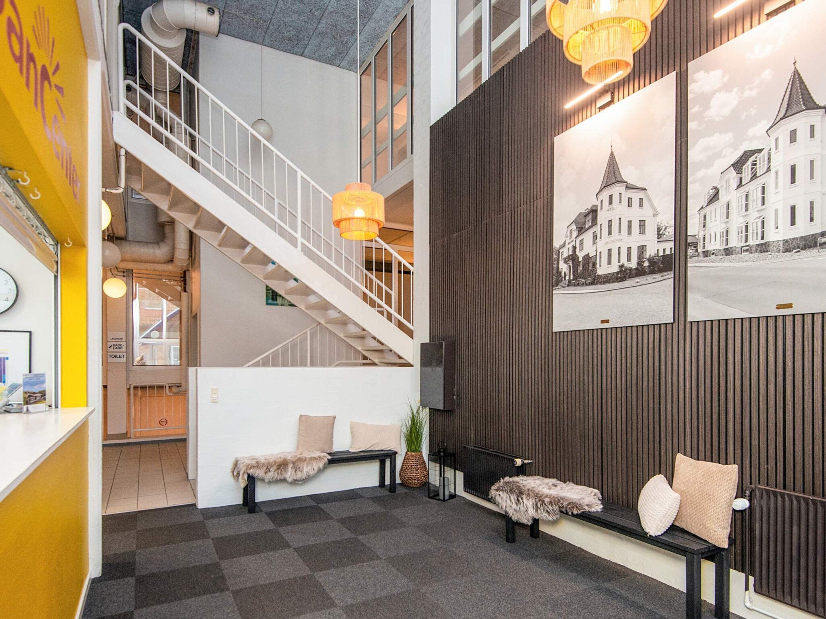 A hotel lobby with a staircase, seating area, and a wall with a cityscape photograph.