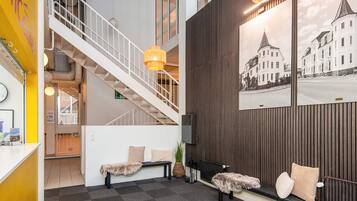 A hotel lobby with a staircase, seating area, and a wall with a cityscape photograph.