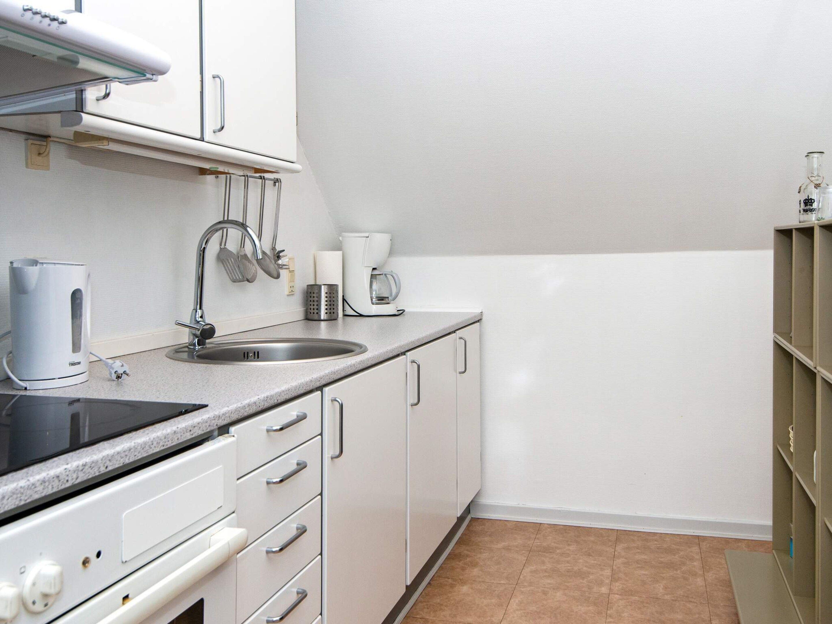 A kitchen with a sink, stove, and cabinets.