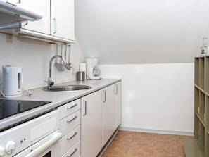 A kitchenette with a stove, sink, and cabinets. - 4 Person Holiday Home in Hejls (Hejls)