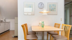 A dining area with a table, chairs, a clock, and a vase. - 4 Person Holiday Home in Hejls (Hejls)
