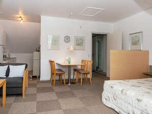 A hotel room with a bed, a desk with two chairs, a small kitchenette, and a door leading to a bathroom. - 4 Person Holiday Home in Hejls (Hejls)