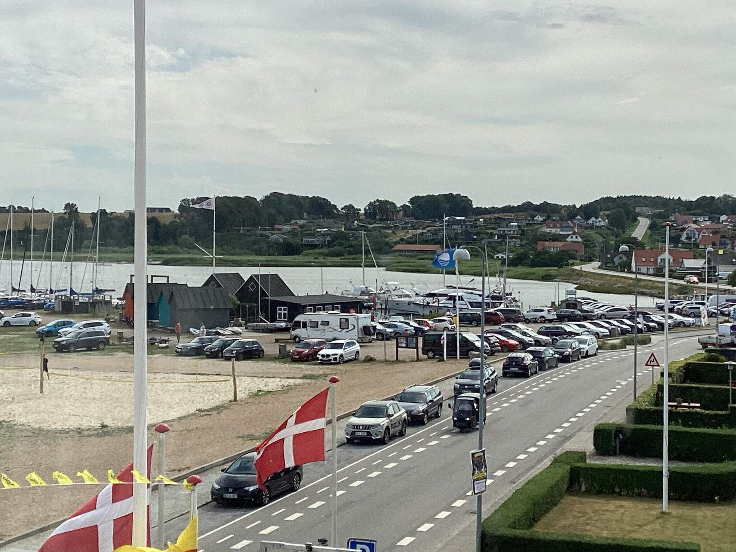 A parking lot with cars and a flagpole with flags.