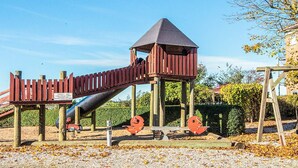 A playground with a slide, climbing structure, and a lookout tower. - 4 Person Holiday Home in Hejls (Hejls)