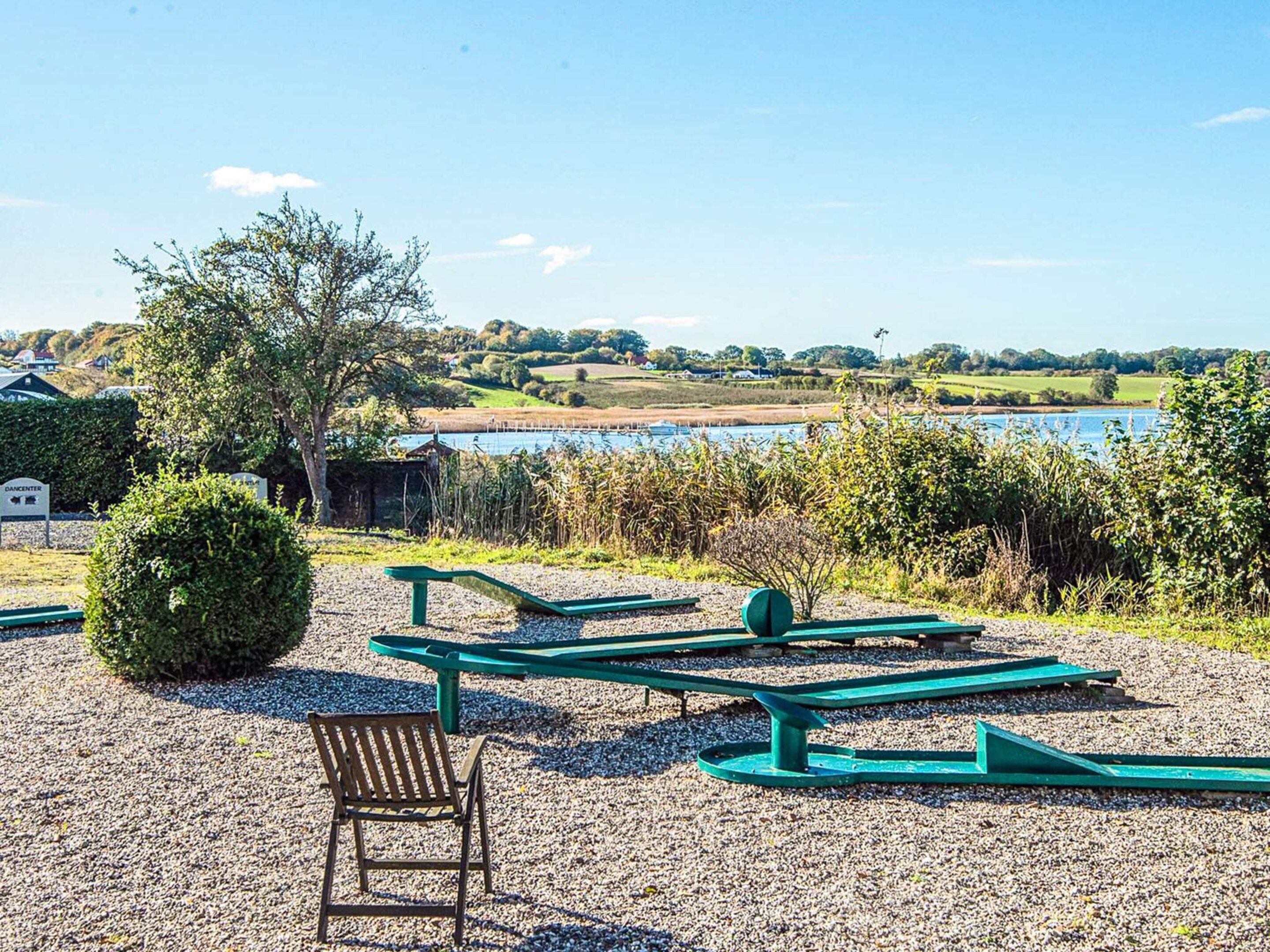 A gravel area with picnic tables and a bench, a small bush, and a sign indicating a dance center.