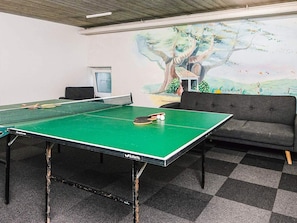 A ping pong table with a net, a sofa, and a mural of a tree on the wall. - 4 Person Holiday Home in Hejls (Hejls)