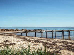 A wooden pier extending into calm waters, surrounded by a sandy beach with sparse vegetation. - 4 Person Holiday Home in Hejls (Hejls)