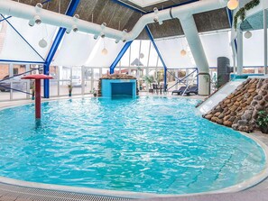 An indoor swimming pool with clear blue water, a rock wall, and a slide. - 4 Person Holiday Home in Hejls (Hejls)