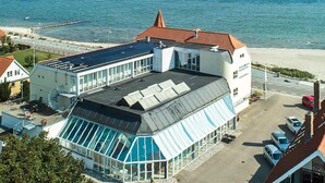 A coastal hotel with a glass conservatory, a swimming pool, and a view of the sea. - 4 Person Holiday Home in Hejls (Hejls)
