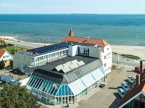 Ett hotell vid kusten med ett glashus, en swimmingpool och utsikt över havet.
