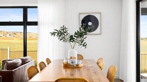 Enjoy meals in this dining area with a long table and wicker chairs, surrounded by a beautiful view.