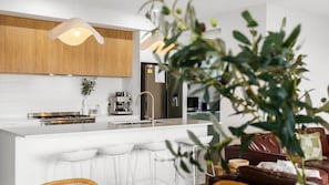 Enjoy cooking in the well-equipped kitchen with a central island, stove, and coffee machine.