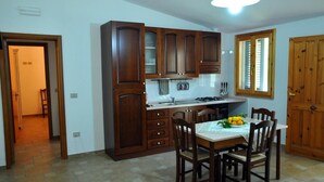 Una cocina con armarios de madera, una mesa de comedor con sillas y una ventana con persianas.